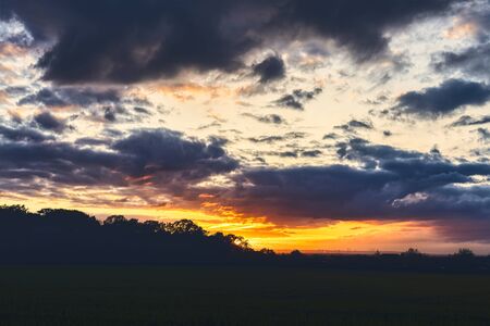beautiful sunset over a meadow with dramatic skyの写真素材