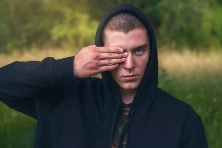 Portrait of a young man with a black hoodie covering his eyesの写真素材