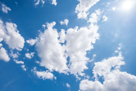 blue sky with clouds and sun, photographed upwards for backgroundsの写真素材