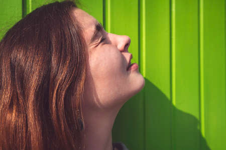 young woman looks at the sun with narrowed eyesの写真素材