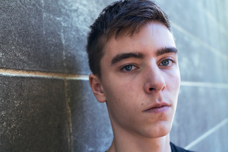 portrait of a serious young man leaning against a wallの写真素材
