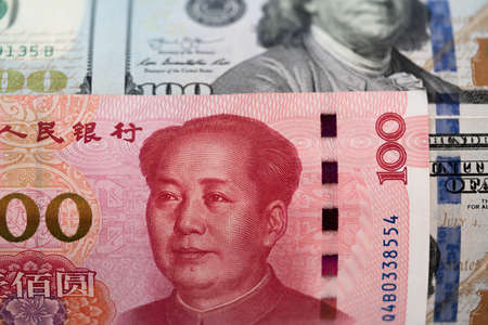 One hundred dollars and One hundred Chinese renminbi RMB bills. CNY background. Closeup of Benjamin Franklin and Mao Zedong . US dollars background. American currency. Macro.の写真素材
