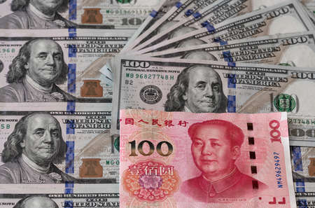 One hundred dollars and One hundred Chinese renminbi RMB bills. CNY background. Closeup of Benjamin Franklin and Mao Zedong . US dollars background. American currency.の写真素材