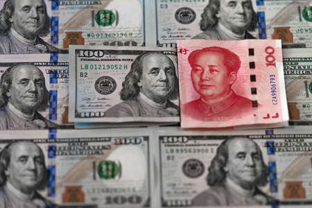 One hundred dollars and One hundred Chinese renminbi RMB bills. CNY background. Closeup of Benjamin Franklin and Mao Zedong . US dollars background. American currency.の写真素材