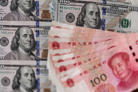 One hundred dollars and One hundred Chinese renminbi RMB bills. CNY background. Closeup of Benjamin Franklin and Mao Zedong . US dollars background. American currency.の写真素材