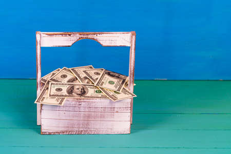 100 dollars money in the wood basket for flowers. Shopping with happiness. Close up of American currency. US dollar background .. Macro shot.の写真素材