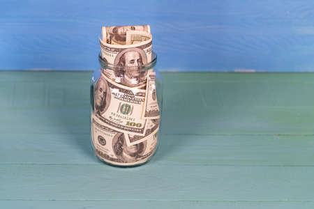 Saving 100 dollar bill Money In Glass Jar. Home economy.の写真素材
