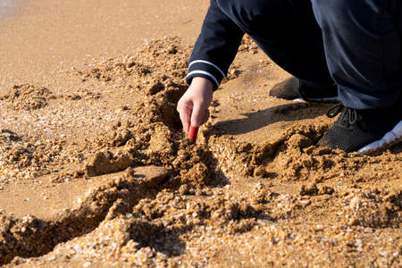 Boy playing with sand on the beach.の写真素材