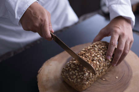 Close up male hand slice loaf of breadの写真素材