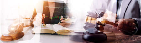 Justice and law concept.Male judge in a courtroom with the gavel, working with, computer and docking keyboard, eyeglasses, on table in morning lightの写真素材