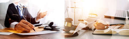 Justice and law concept.Male judge in a courtroom with the gavel, working with, computer and docking keyboard, eyeglasses, on table in morning lightの写真素材