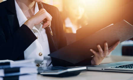 Woman accountant use calculator and computer with holding pen on