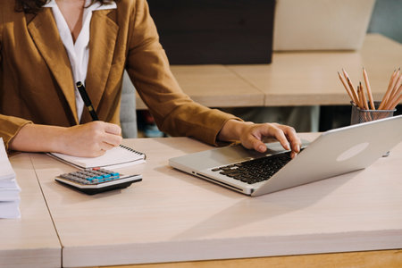 Woman accountant use calculator and computer with holding pen on