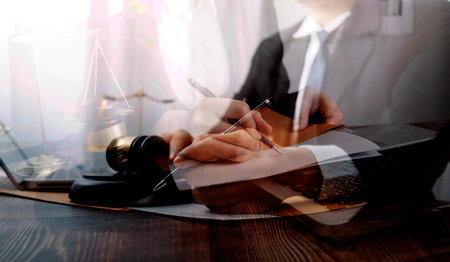 Business and lawyers discussing contract papers with brass scale on desk in office. Law, legal services, advice, justice and law concept picture with film grain effectの写真素材