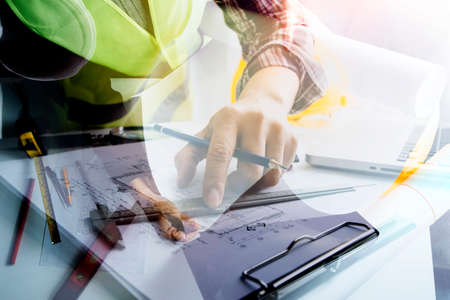 business hand working and laptop with on on architectural project at construction site at office...
