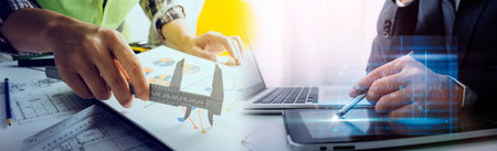 Two colleagues discussing data working and tablet, laptop with on on architectural project at...