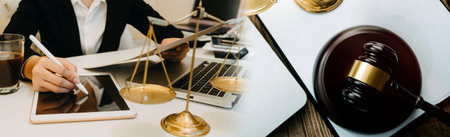 Business and lawyers discussing contract papers with brass scale on desk in office. Law, legal services, advice, justice and law concept picture with film grain effectの写真素材