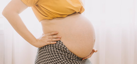Young adult pregnant woman touching big naked belly with hands. Showing shape. Pregnancy concept....