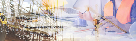 Two colleagues discussing data working and tablet, laptop with on on architectural project at construction site at desk in officeの写真素材