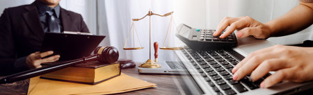 Justice and law concept.Male judge in a courtroom with the gavel, working with, computer and docking keyboard, eyeglasses, on table in morning lightの写真素材