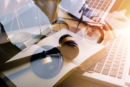 Justice and law concept.Male judge in a courtroom with the gavel, working with, computer and docking keyboard, eyeglasses, on table in morning lightの写真素材