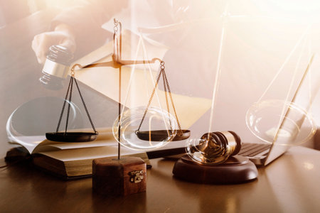 Justice and law concept.Male judge in a courtroom with the gavel, working with, computer and docking keyboard, eyeglasses, on table in morning lightの写真素材