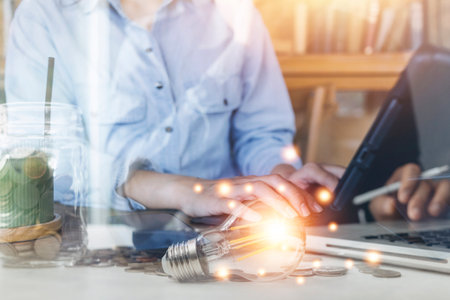 Businessman hands working with finances about cost and calculator and laptop with tablet, smartphone at office in morning lightの写真素材