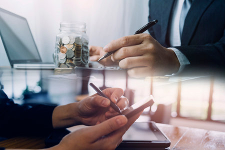 Business partnership coworkers using a tablet to analysis graph company financial budget report and cost work progress and planning for future in office room.の写真素材