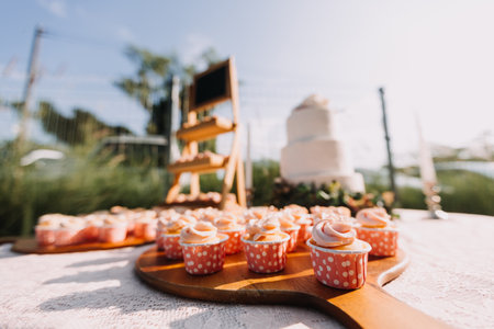 Gourmet cupcakes with white buttercream frosting and sprinkles on wooden background
