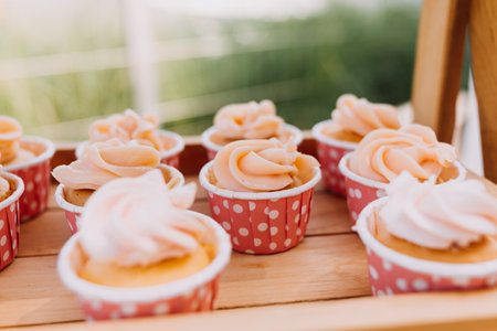 Gourmet cupcakes with white buttercream frosting and sprinkles on wooden background