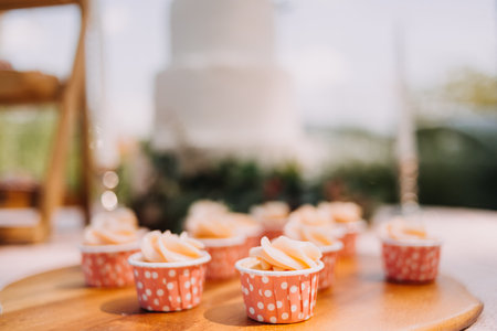 Gourmet cupcakes with white buttercream frosting and sprinkles on wooden background
