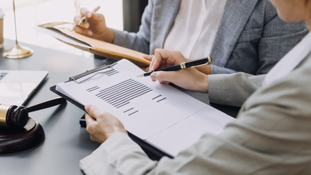 law books and scales of justice on desk in library of law firm. jurisprudence legal education concept.の写真素材