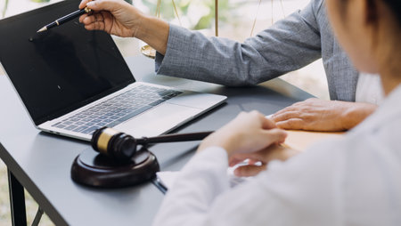 Business and lawyers discussing contract papers with brass scale on desk in office. Law, legal services, advice, justice and law concept picture with film grain effectの写真素材
