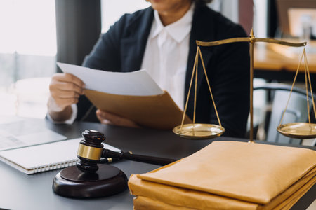 Justice and law concept.Male judge in a courtroom with the gavel, working with, computer and docking keyboard, eyeglasses, on table in morning lightの写真素材