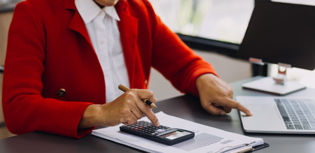 Businessman hands working with finances about cost and calculator and laptop with tablet, smartphone at office in morning lightの写真素材