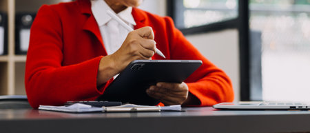 Businessman hands working with finances about cost and calculator and laptop with tablet, smartphone at office in morning lightの写真素材