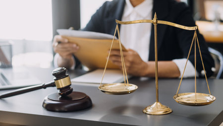 Justice and law concept.Male judge in a courtroom with the gavel, working with, computer and docking keyboard, eyeglasses, on table in morning lightの写真素材