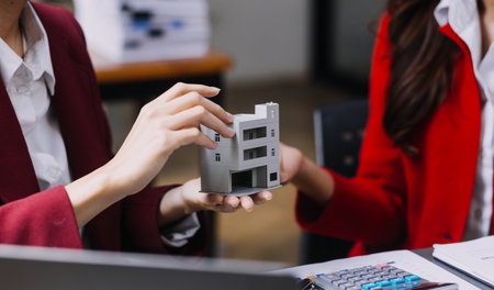 Discussion with a real estate agent, House model with agent and customer discussing for the contract to buy, get insurance or loan real estate or property.の写真素材