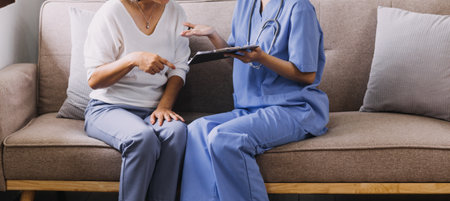 Homecare nursing service and elderly people cardiology healthcare. Close up of young hispanic female doctor nurse check mature caucasian man patient heartbeat using stethoscope during visitの写真素材