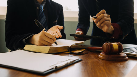 Business and lawyers discussing contract papers with brass scale on desk in office. Law, legal services, advice, justice and law concept picture with film grain effectの写真素材