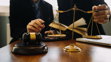 Business and lawyers discussing contract papers with brass scale on desk in office. Law, legal services, advice, justice and law concept picture with film grain effectの写真素材