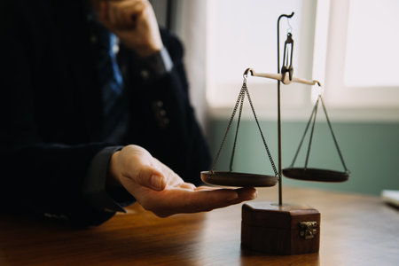 Business and lawyers discussing contract papers with brass scale on desk in office. Law, legal services, advice, justice and law concept picture with film grain effectの写真素材