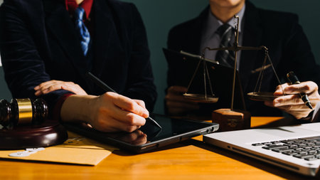 Business and lawyers discussing contract papers with brass scale on desk in office. Law, legal services, advice, justice and law concept picture with film grain effectの写真素材
