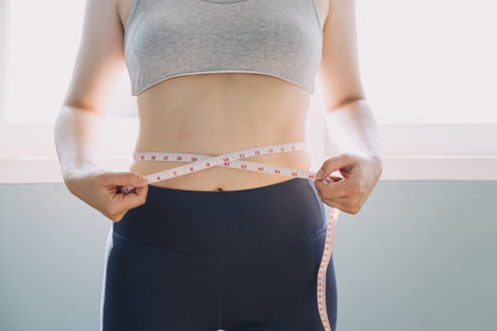 Beautiful fat woman with tape measure She uses her hand to squeeze the excess fat that is isolated on a white background. She wants to lose weight, the concept of surgery and break down fat under theの写真素材