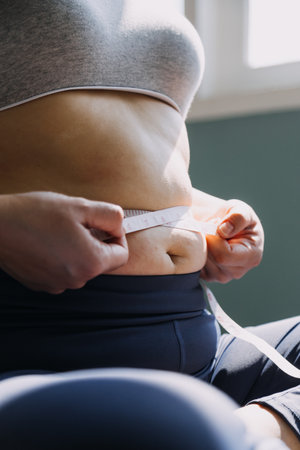 Beautiful fat woman with tape measure She uses her hand to squeeze the excess fat that is isolated on a white background. She wants to lose weight, the concept of surgery and break down fat under theの写真素材