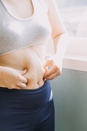 Beautiful fat woman with tape measure She uses her hand to squeeze the excess fat that is isolated on a white background. She wants to lose weight, the concept of surgery and break down fat under theの写真素材