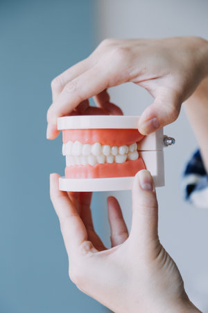 Stomatology concept, partial portrait of girl with strong white teeth looking at camera and smiling, fingers near face. Closeup of young woman at dentist's, studio, indoorsの写真素材