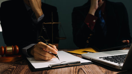 Business and lawyers discussing contract papers with brass scale on desk in office. Law, legal services, advice, justice and law concept picture with film grain effectの写真素材