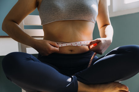 Beautiful fat woman with tape measure She uses her hand to squeeze the excess fat that is isolated on a white background. She wants to lose weight, the concept of surgery and break down fat under theの写真素材