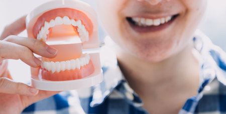 Stomatology concept, partial portrait of girl with strong white teeth looking at camera and smiling, fingers near face. Closeup of young woman at dentist's, studio, indoorsの写真素材